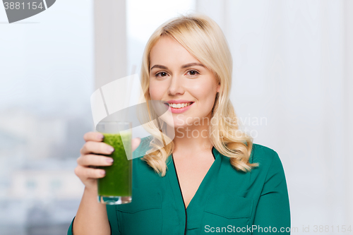 Image of smiling woman drinking juice or smoothie at home