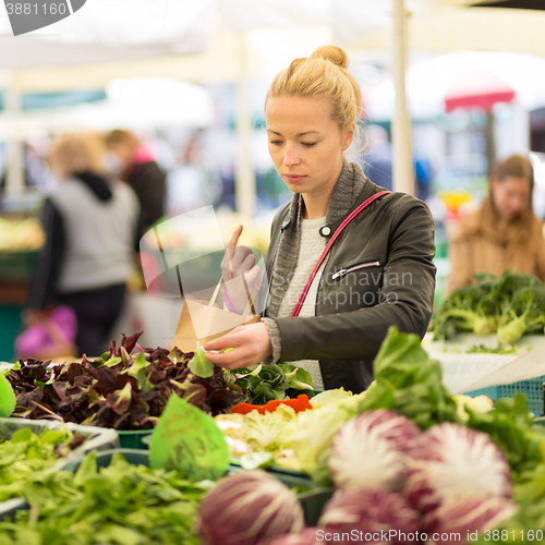 Image of Woman buying vegetable at local food market. 