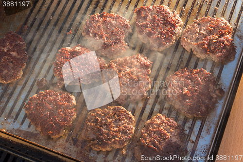 Image of Beef burgers being grilled on barbecue.