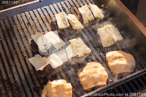 Image of Beef burgers being grilled on barbecue.