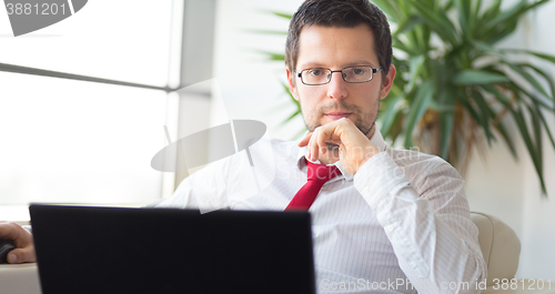 Image of Portrait of businessman working on laptop computer