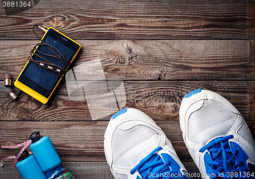 Image of Sports equipment - sneakers, skipping rope, smartphone and headphones. Sport background on wooden floor, top view.