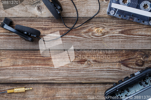 Image of Cassette tape, cassette player and headphones over wooden table. top view.