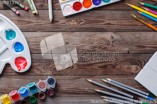 Image of Paper, watercolors, paint brush and some art stuff on wooden   table