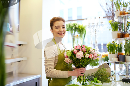 Image of smiling florist woman making bunch at flower shop