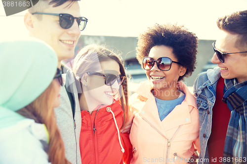 Image of happy teenage friends in shades talking on street