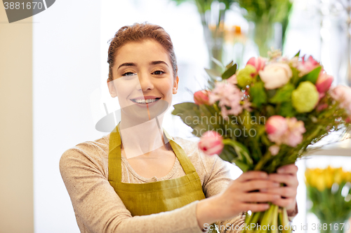 Image of smiling florist woman making bunch at flower shop