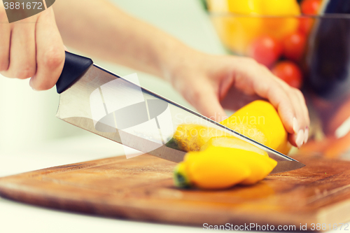 Image of close up of hands chopping squash with knife