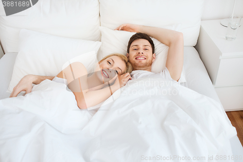 Image of happy couple lying in bed at home