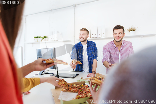 Image of happy business team eating pizza in office