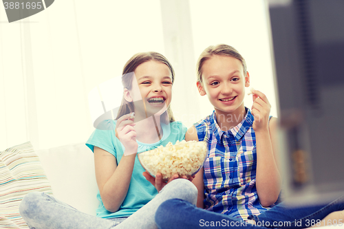 Image of happy girls with popcorn watching tv at home