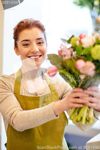 Image of smiling florist woman making bunch at flower shop