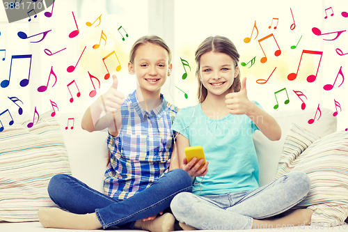 Image of happy girls with smartphone sitting on sofa