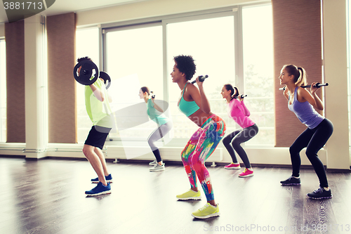 Image of group of people exercising with barbell in gym