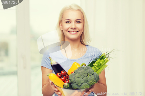 Image of smiling young woman with vegetables at home