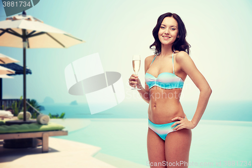 Image of happy young woman in swimsuit drinking champagne