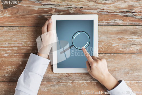 Image of close up of male hands with magnifier on tablet pc