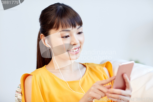 Image of happy asian woman with smartphone and earphones