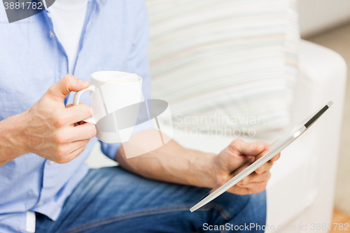 Image of close up of man with tablet pc and tea cup at home
