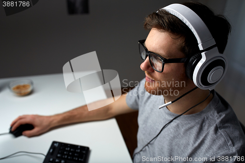 Image of man in headset playing computer video game at home