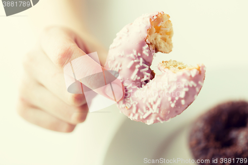 Image of close up of hand holding bitten glazed donut