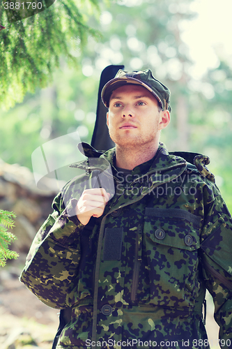 Image of young soldier or hunter with gun in forest