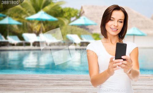 Image of happy woman taking selfie by smartphone over beach