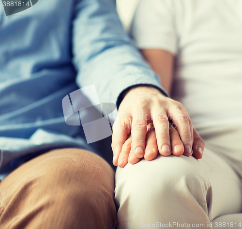 Image of close up of happy male gay couple holding hands