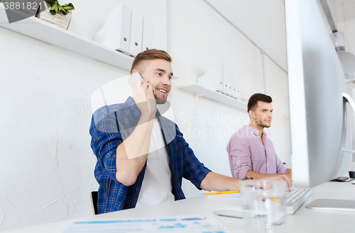 Image of happy creative man calling on cellphone at office