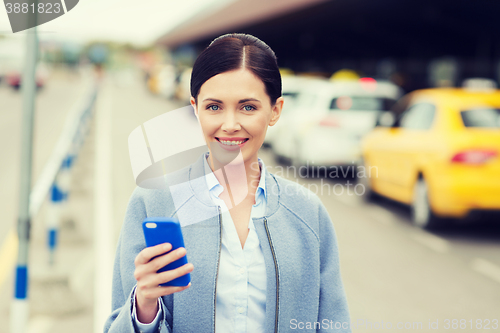 Image of smiling woman with smartphone over taxi in city