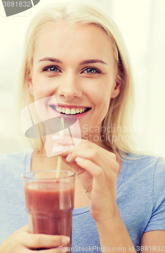 Image of smiling woman drinking juice or shake at home