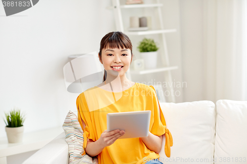 Image of happy young asian woman with tablet pc at home