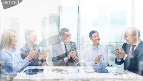 Image of business team with laptop clapping hands