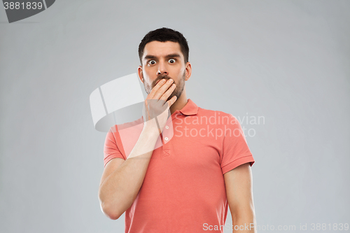 Image of scared man in polo t-shirt over gray background