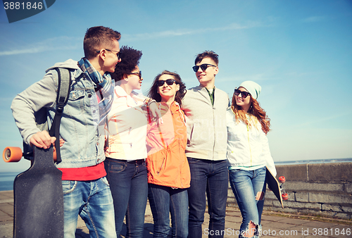 Image of happy teenage friends with longboards on street