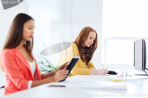 Image of creative female office worker writing to notebook