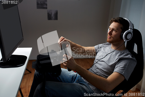 Image of man playing car racing video game at home