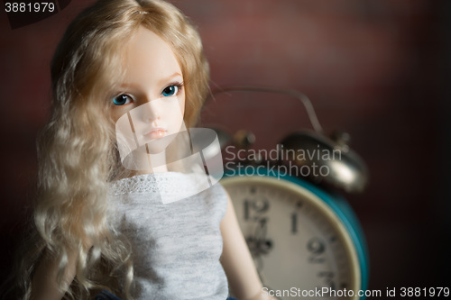 Image of doll on the background of the old clock.