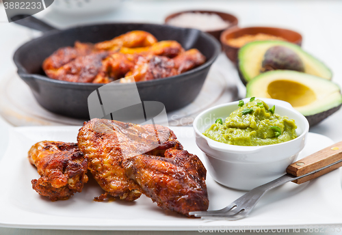 Image of Grilled chicken legs and wings with guacamole