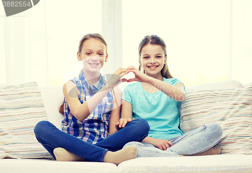 Image of happy little girls showing heart shape hand sign