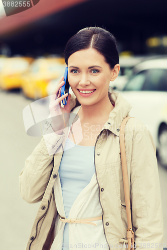 Image of smiling woman with smartphone over taxi in city