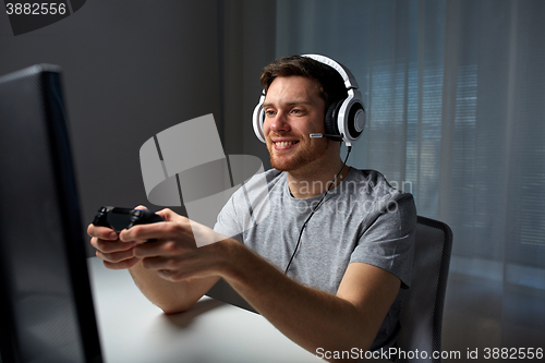 Image of man in headset playing computer video game at home