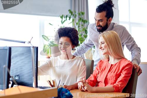 Image of happy creative team with computer in office