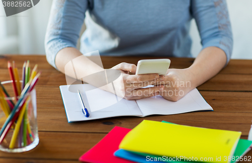 Image of close up of student with smartphone and notebook