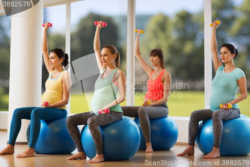 Image of happy pregnant women exercising on fitball in gym