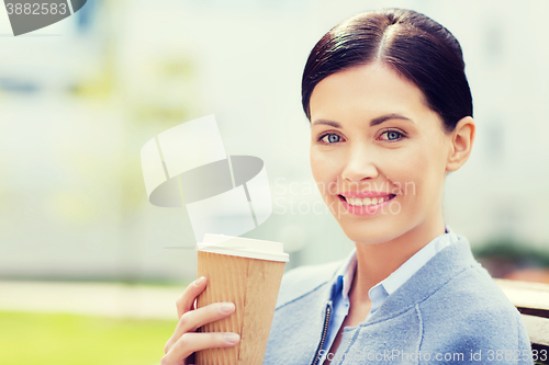 Image of smiling woman drinking coffee outdoors