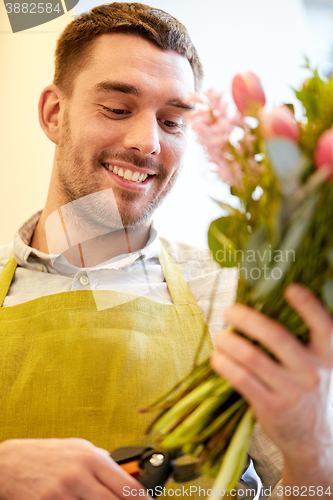 Image of smiling florist man making bunch at flower shop