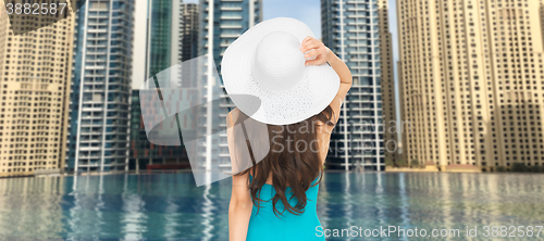 Image of woman in sun hat from back over dubai city pool