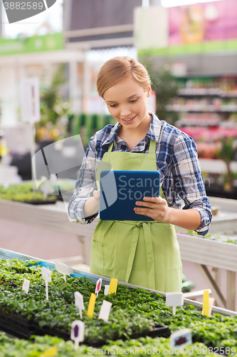 Image of happy woman with tablet pc in greenhouse