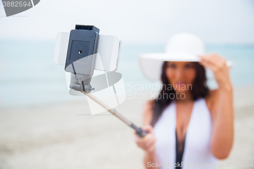 Image of smiling young woman taking selfie with smartphone